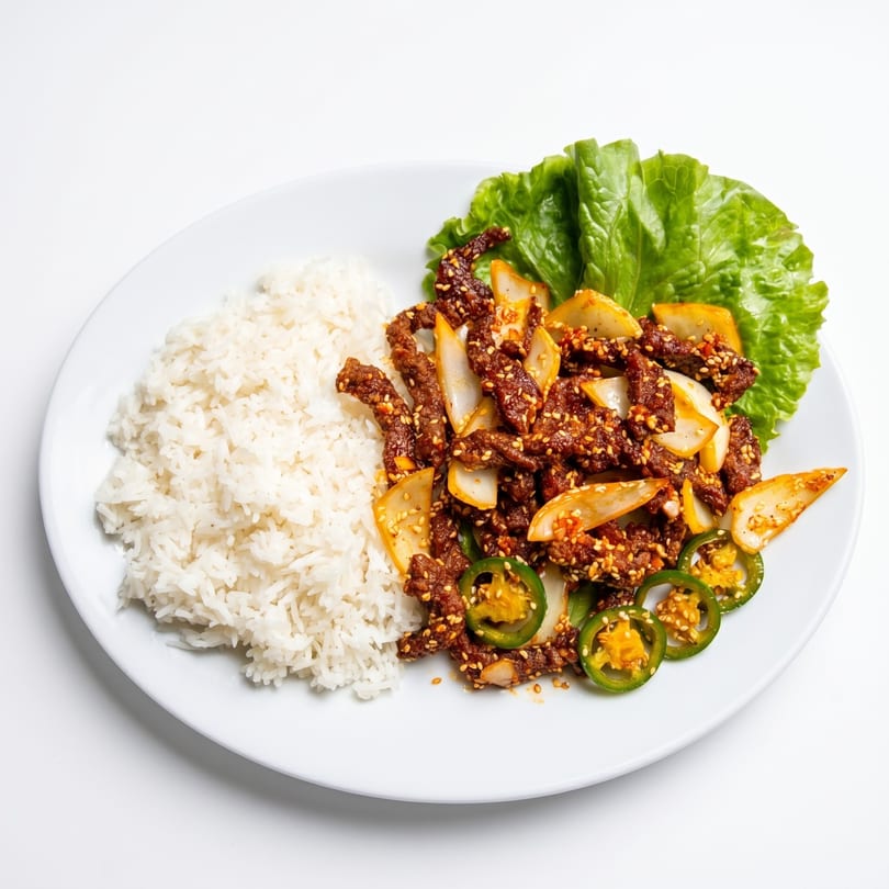 Spicy beef with onions, jalapeños, and sesame seeds, served with white rice and lettuce.